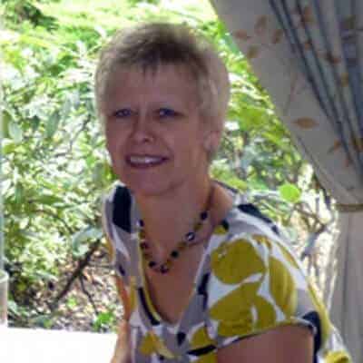 Smiling person near window with floral top.