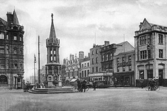 Historic town square with monument and buildings.