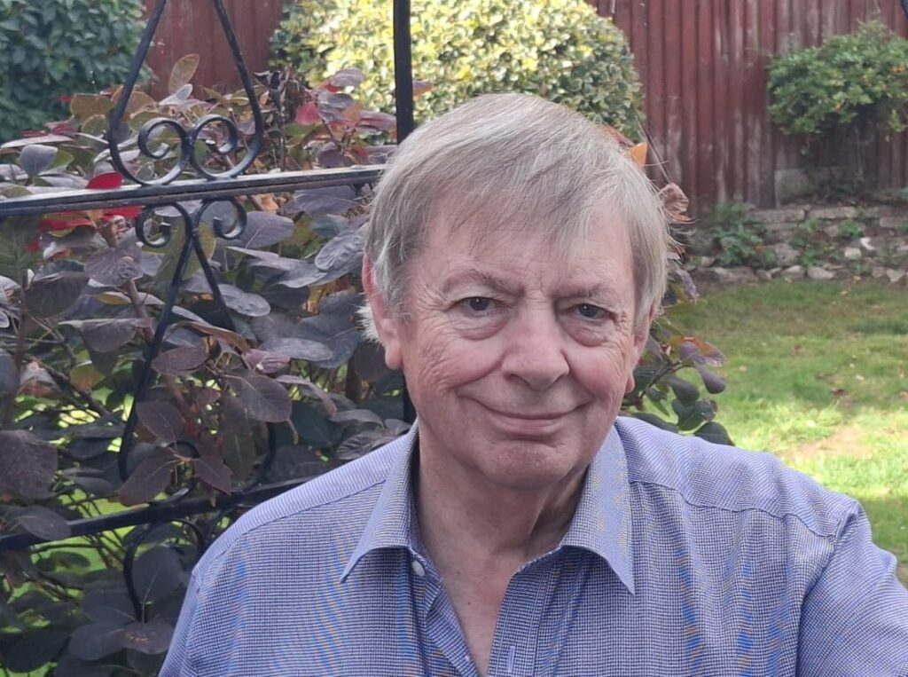 Smiling older man sitting in a leafy garden