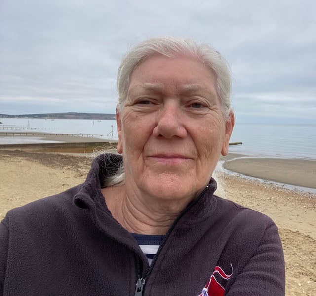 Older woman taking a selfie on an overcast beach